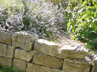 Locker aufgesetzte Trockenmauer aus Muschelkalk Bruchstein als Einfassung eines Hochbeets.